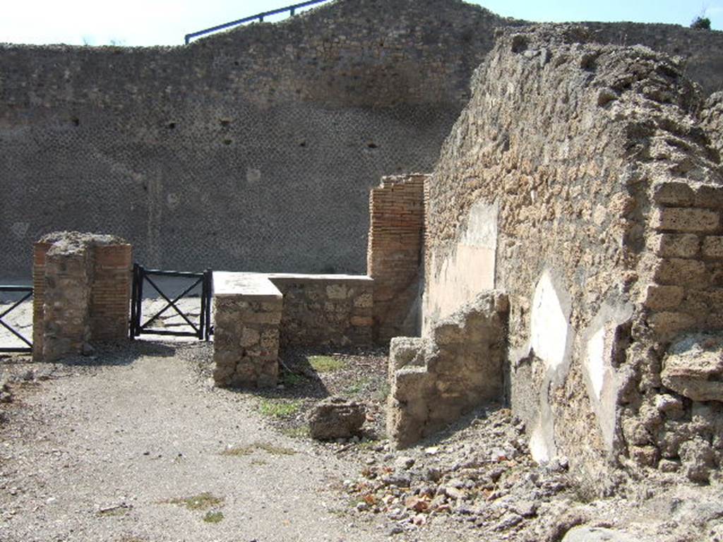 I.2.13 Pompeii. September 2005. Taken from rear. Looking west towards site of ruined small rear room or cupboard, and bar-room onto Via Stabiana and the Little Theatre.  On the left, behind the brick pilaster separating two doorways, would have been the site of the south wall of I.2.13. I.2.14 is visible on the extreme right of the picture.

