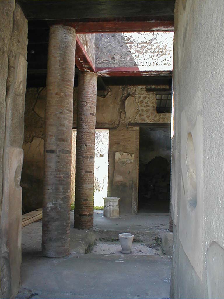 VI.15.9 Pompeii. September 2004. Entrance corridor, looking west to atrium.
According to Richardson, this tiny atrium house had a very efficient design.
The atrium is entered by short fauces flanked by cubicula with windows to the street.
The atrium is almost square, Tetrastyle with columns of naked brick that supported a second floor.
The second floor was a gallery lit by large rectangular windows into the compluvium well.
It was accessible by a small staircase against the north wall of the atrium.
Although it must have made the atrium rather dark, it made living space available over the atrium, as well as over the cubicula at the front of the house.
On the far side of the atrium, opened an ample triclinium and the service area.
This service area in the south-west corner of the house was lit by a second light-well and had a second storey of its own, possibly just a loft for storage.
See Notizie degli Scavi di Antichit, 1897, 38-39, 62-64.
See Richardson, L., 1988. Pompeii: An Architectural History. Baltimore: John Hopkins University Press. (p.345-6)
(Note  the staircase is actually against the south wall of the atrium)
