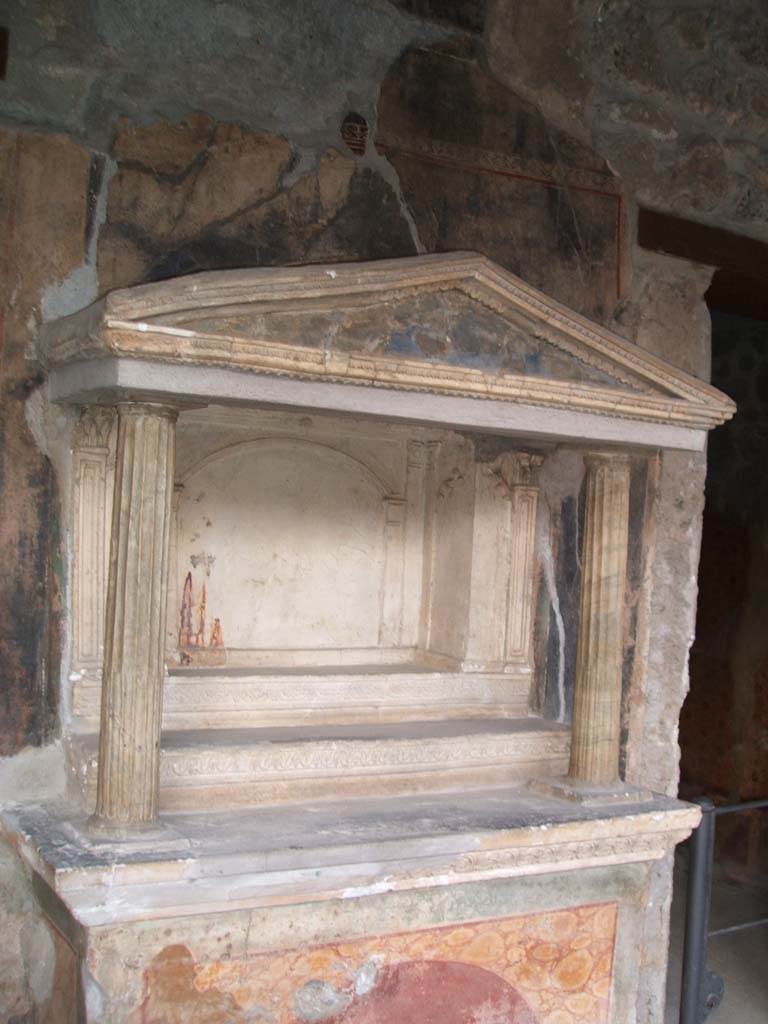 VI.16.7 Pompeii. December 2004. Room F, north portico. Household lararium. 
Two fluted marble columns, with architrave and pediment. 
The rectangular niche has its floor divided into three levels by two high steps (shelves).
