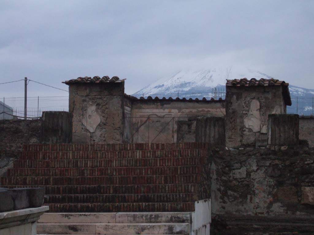 VII.7.32 Pompeii. December 2005. Looking north to steps, podium and cella, with snow covered Vesuvius in background.