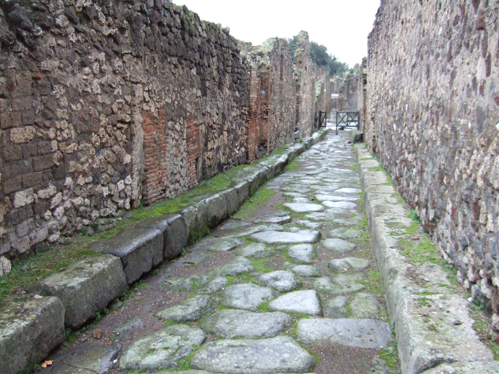 VII.14 Pompeii, on left. December 2005.    Vicolo della Maschera looking south.       Side wall of VII.13.14, on right.