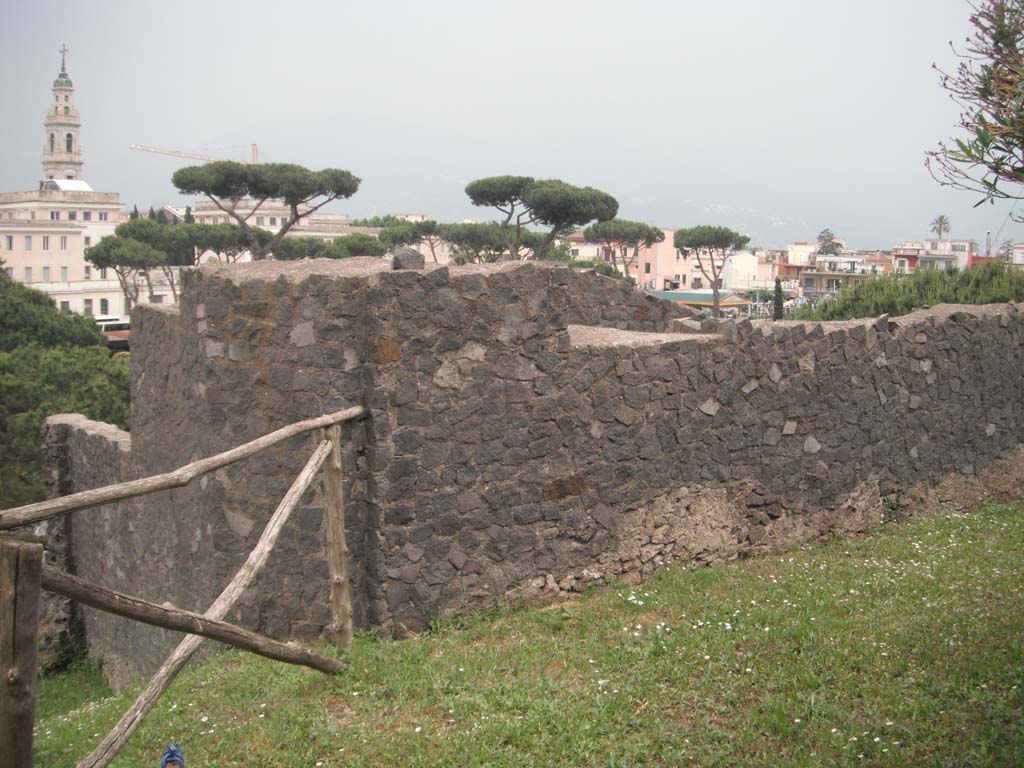 Tower V, Pompeii. May 2011.
Looking south-east from rear of Tower towards modern Pompeii. Photo courtesy of Ivo van der Graaff.
According to Van der Graaf –
“Tower V present extensive toothed brickwork in its quoins and southern flank. 
The construction technique is similar to Tower II, implying that its refurbishment occurred in the early colony.
The ground floor inside the tower has no pavement. When or what event caused its removal is unclear. 
Modern masonry composes much of the upper structure.
If restored correctly, the tower displays a floating rear entrance and side doors that are the result of lowering the agger associated with the construction of the amphitheatre in 70 BCE.
A sliver of surviving opus vittatum mixtum masonry, set below a modern restoration on the first corner of the stairway, hints at a post-earthquake intervention. Considering that the entire upper arcade of the neighbouring amphitheatre displays similar brickwork, it seems likely that both structures received contemporary post-earthquake repairs.”
See Van der Graaf, I. (2018). The Fortifications of Pompeii and Ancient Italy. Routledge, (p.132-133).

