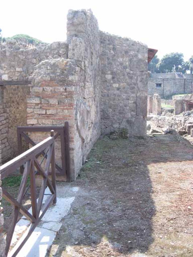 I.5.2 Pompeii. September 2010. From entrance doorway, looking west along Vicolo del Conciapelle towards Via Stabiana. This also shows the portico wall of I.5.1. Along the wall between entrances I.5.2 and I.5.1 was a bench, and the remains of a street altar can be seen. Photo courtesy of Drew Baker.