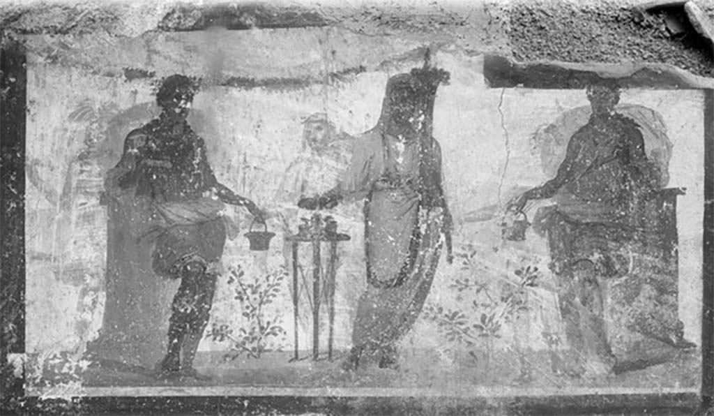 Street shrine outside IX.12.7. Detail from 1912 photograph.
Top right of the four paintings was a painting of two Lares in green tunics leaning on pillars. 
A genius was making a sacrifice at a portable altar. 
Three other similar people from an older picture were also visible through the white background. 
See Fröhlich, T., 1991. Lararien und Fassadenbilder in den Vesuvstädten. Mainz: von Zabern. (p. 339, F71, T: 58,2).