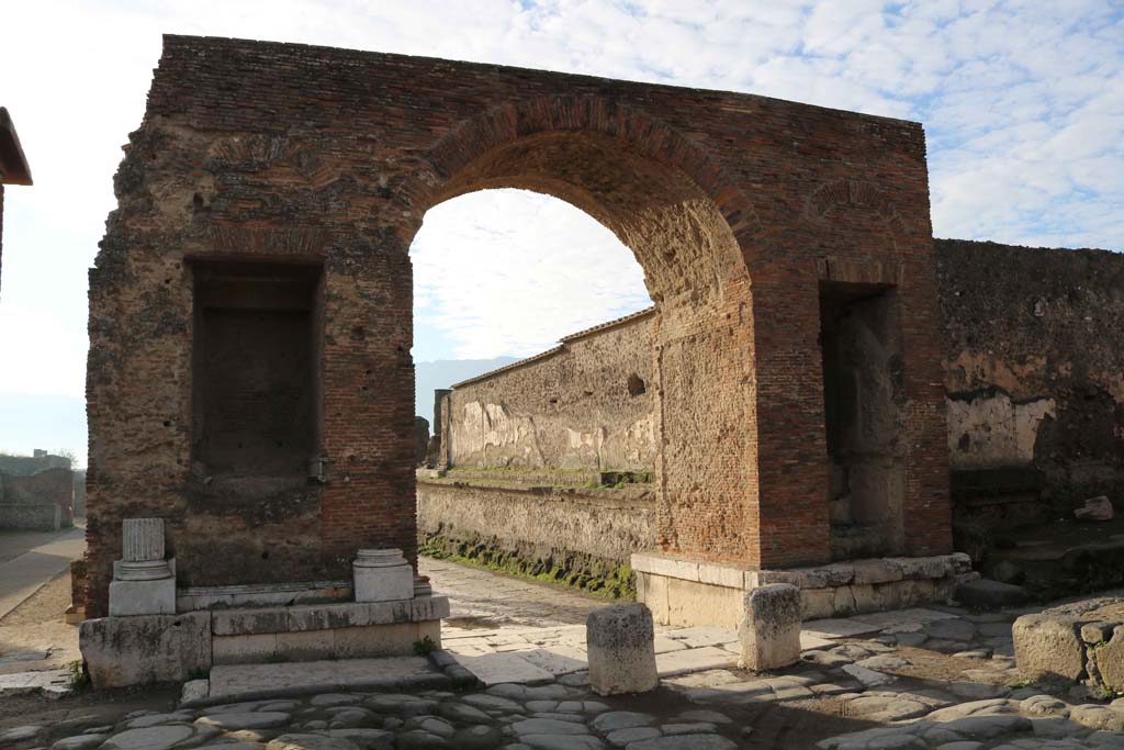 Arch at north-east end of the Forum. December 2018. 
Looking south-west from Via del Foro, into the Forum. Photo courtesy of Aude Durand.