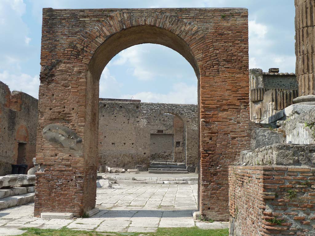 Arched entrance in north-west corner of Pompeii Forum, May 2010. 
Looking north through Arch of Augustus to the arched entrance with its steps.