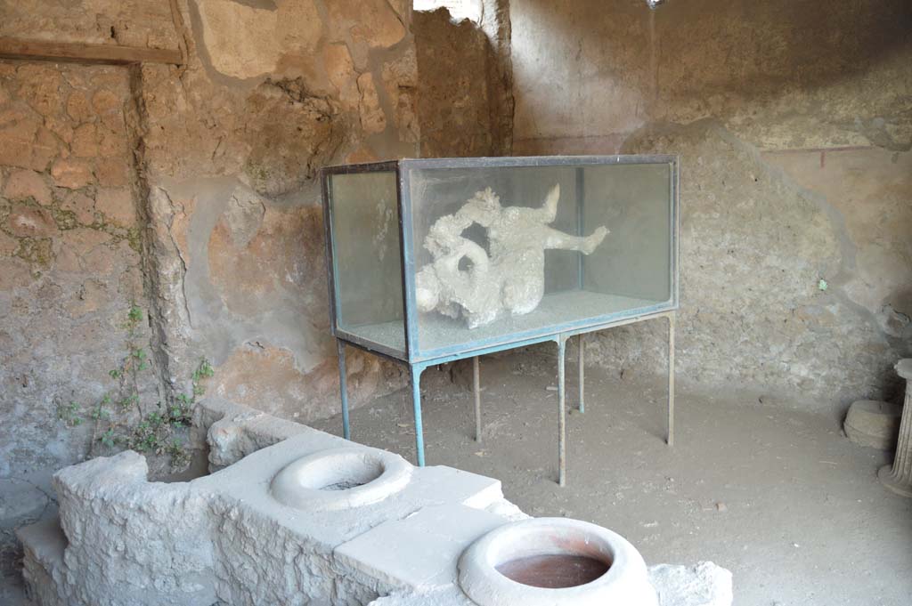 III.6.1 Pompeii. October 2017. Looking across east side of counter and hearth towards glass case with cast of victim 27 in north-east corner of bar-room.
Foto Taylor Lauritsen, ERC Grant 681269 DÉCOR.