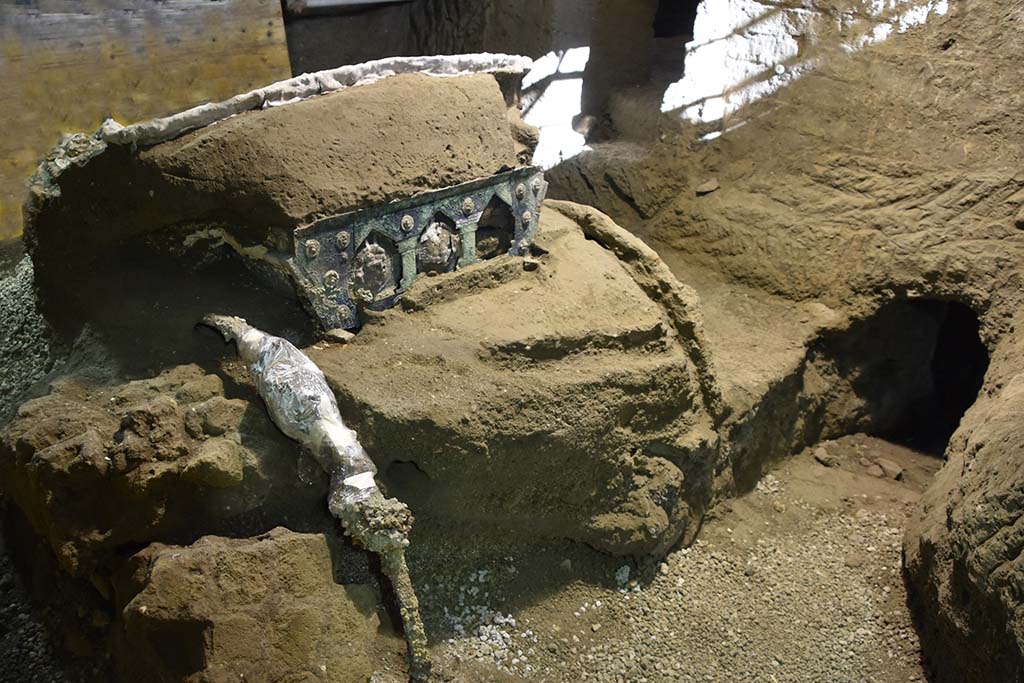 Cività Giuliana. February 2021. The four-wheeled processional chariot which has emerged intact from the excavation of the suburban villa of Cività Giuliana.
A large ceremonial chariot with four wheels, along with its iron components, beautiful bronze and tin decorations, mineralised wood remains and imprints of organic materials (from the ropes to the remains of floral decoration), has been discovered almost intact in the portico facing the stable where, in 2018, the remains of 3 equidae, including a horse still in its harness, had already been found.
This is an exceptional discovery, not only because it adds an additional element to the history of this dwelling and the story of the last moments in the lives of those who lived in it, as well as more generally to our understanding of the ancient world, but above all because it represents a unique find - which has no parallel in Italy thus far - in an excellent state of preservation.
Cività Giuliana. Febbraio 2021.  Il Carro da parata a quattro ruote emerso integro dallo scavo della villa suburbana in località Civita Giuliana.
Un grande carro cerimoniale a quattro ruote, con i suoi elementi in ferro, le bellissime decorazioni in bronzo e stagno, i resti lignei mineralizzati, le impronte degli elementi organici (dalle corde a resti di decorazioni vegetali), è stato rinvenuto quasi integro nel porticato antistante alla stalla dove già nel 2018 erano emersi i resti di 3 equidi, tra cui un cavallo bardato.
Un ritrovamento eccezionale, non solo perché aggiunge un elemento in più alla storia di questa dimora, al racconto degli ultimi istanti di vita di chi abitava la villa, e più in generale alla conoscenza del mondo antico, ma soprattutto perché restituisce un reperto unico - mai finora rinvenuto in Italia – in ottimo stato di conservazione.
Photograph © Parco Archeologico di Pompei.
