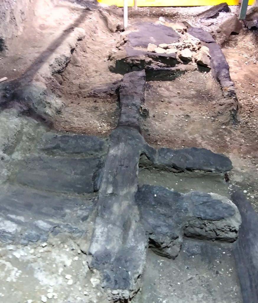 Cività Giuliana. February 2021. 
An excavation was subsequently carried out which reached a depth of 6 metres relative to the road level, with stabilisation both of the excavation fronts and the robust masonry structures - which were preserved up to a level of 4 metres - that emerged over the course of the investigations.
From the very beginning, the excavation of the room where the chariot was found revealed its exceptional nature: the area in question is in fact a double-level portico which opens onto an uncovered courtyard, and which features the carbonised wooden ceiling with its network of beams, preserved in its entirety.
Archaeobotanical analyses have been carried out on the wood, which have shown that the ceiling was constructed of deciduous oak wood (Quercus sp. – cf. robur - English oak), a timber which was frequently used in the Roman age for structural elements. The carbonised wooden structure of the door on the southern side of the room, which connected the portico to the stable where the three equids were recently discovered, was also preserved, and upon analysis was identified as beechwood.
The wooden ceiling was carefully consolidated, cleaned, and removed from the excavation area in order to permit the investigations to continue.
Cività Giuliana. Febbraio 2021.  
Si è quindi proceduto ad uno scavo che ha raggiunto i 6 metri di profondità rispetto al piano stradale, mettendo in sicurezza sia i fronti di scavo che le possenti strutture murarie – conservate fino a 4 m. - che emergevano nel corso delle indagini
Lo scavo dell’ambiente dove si è rinvenuto il carro ha mostrato fin dall’inizio la sua eccezionalità: si tratta infatti di un portico a due piani, aperto su una corte scoperta, che conservava in tutta la sua interezza il solaio ligneo carbonizzato con il suo ordito di travi.
Si sono condotte analisi archeobotaniche del legno che hanno mostrato come il solaio fosse stato realizzato in legno di quercia decidua (Quercus sp. – cfr. robur - farnia), un legno frequentemente utilizzato in età romana per realizzare elementi strutturali. Anche la porta sul lato sud della stanza, che metteva in comunicazione il portico con la stalla dove negli scorsi anni si sono rinvenuti 3 equidi, conservava la sua struttura in legno carbonizzato che è stato analizzato e identificato come faggio.
Il solaio ligneo è stato accuratamente consolidato, pulito e rimosso dall’area di scavo per permettere il proseguimento delle indagini.
Photograph © Parco Archeologico di Pompei.