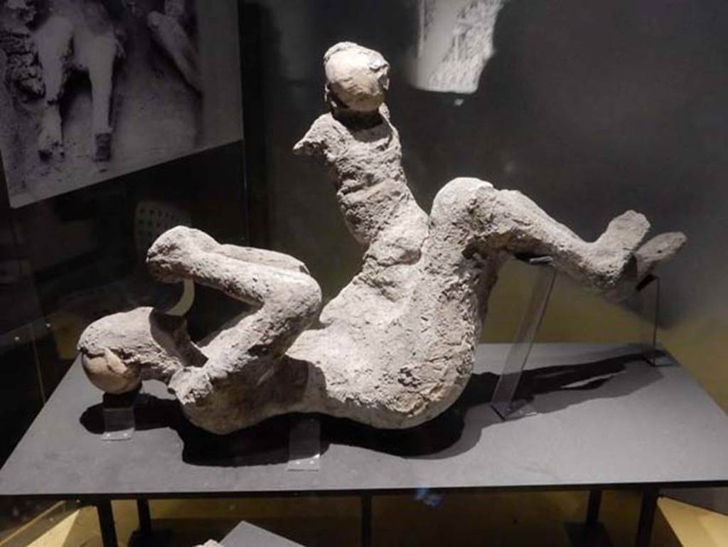 VI.17.42, Pompeii, May 2018. 
Plaster cast of a man (52) and child (51) found in the corridor leading to the garden area. Photo courtesy of Buzz Ferebee.
According to Estelle Lazer, this individual (52) is clearly a mature adult, but there is insufficient evidence to make an attribution of the sex of this victim.
See Lazer E., et al. 2020. Inside the Casts of the Pompeian Victims: Results from the First Season of the Pompeii Cast Project In 2015. Papers of the British School at Rome.
Victim 51 is a male child aged less than 6 years, probably 5 to 6 years old.
The body was found under staircase 30 of the Casa dell Bracciale d’Oro between the 3rd and 6th of June 1974.
Imprints from a tunic are vaguely identifiable on the chest, shoulders, back and legs of the victim.
See Osanna, N., Capurso, A., e Masseroli, S. M., 2021. I Calchi di Pompei da Giuseppe Fiorelli ad oggi: Studi e Ricerche del PAP 46, p. 439-440, Calco n. 51.
Victim 52, previously identified as female, is now identified as a male aged not less than 20 years old.
The body was found under staircase 30 of the Casa dell Bracciale d’Oro between the 3rd and 6th of June 1974.
Imprints from the clothing are vaguely identifiable on the torso and legs.
See Osanna, N., Capurso, A., e Masseroli, S. M., 2021. I Calchi di Pompei da Giuseppe Fiorelli ad oggi: Studi e Ricerche del PAP 46, p. 441-443, Calco n. 52.