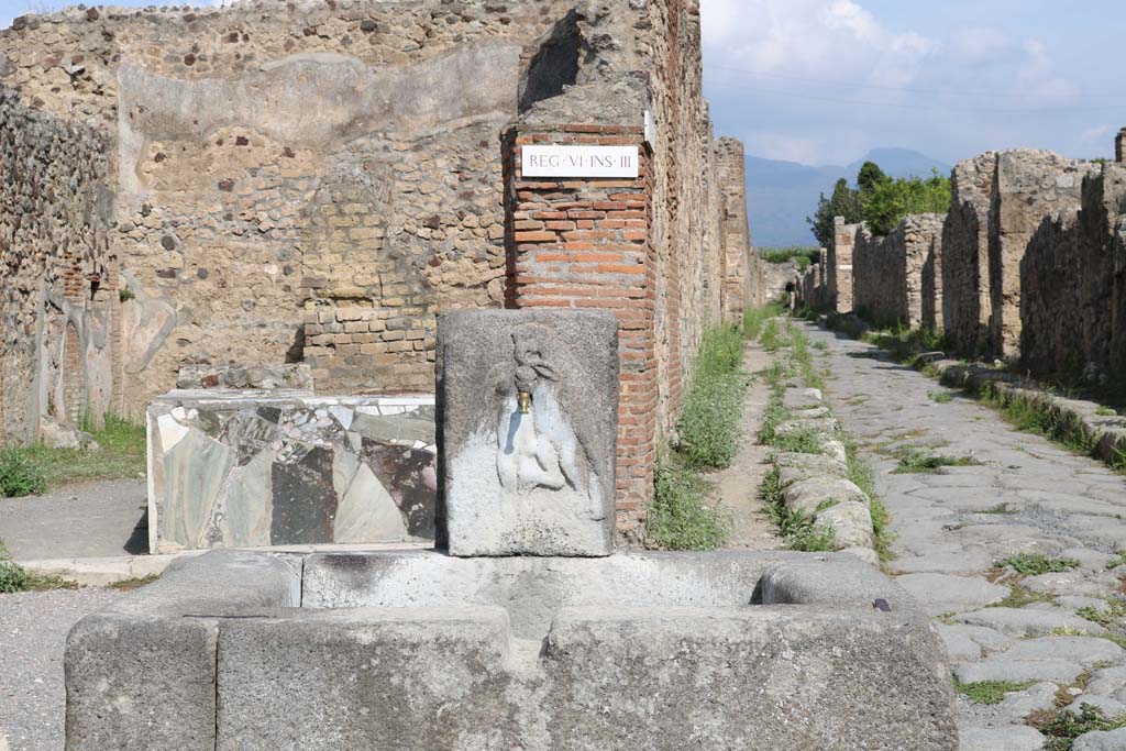 Fountain outside VI.3.20. December 2018. 
Looking north from fountain at junction with Vicolo di Modesto, on right, and Via Consolare. Photo courtesy of Aude Durand.
