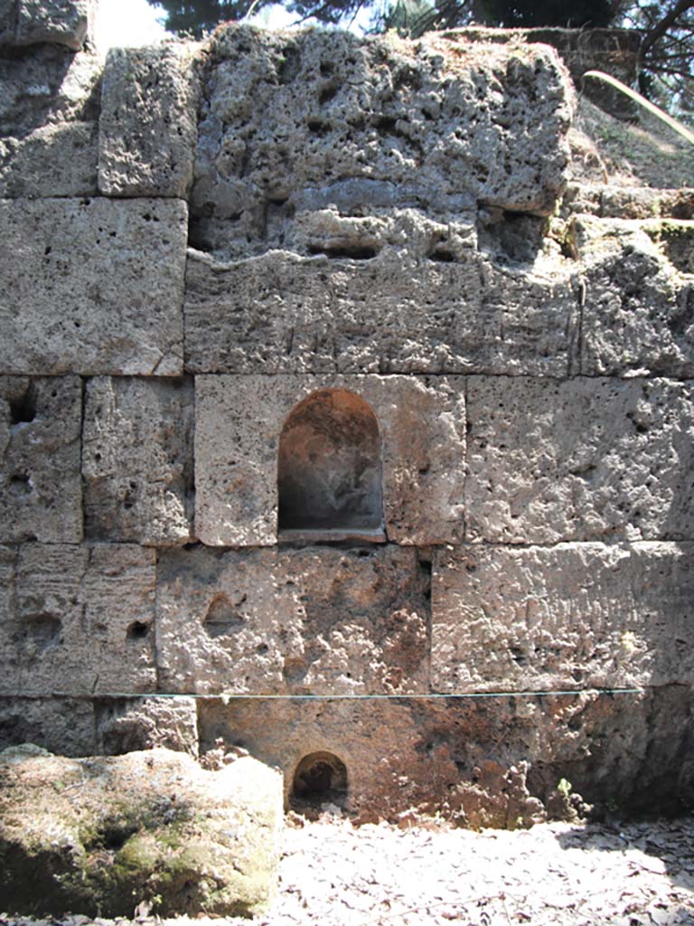 Porta Stabia, Pompeii. May 2011. East side, wall with two niches. Photo courtesy of Ivo van der Graaff.
According to Van der Graaff –
“Minerva was also present at the Porta Stabia (see Fig.8.2). 
The gate still carries two small niches carved into the eastern wall of the court, meant to evoke a deity protecting the walls as well as travellers traversing the liminal space (Note 9).
At the time of their discovery, the upper niche retained traces of plaster coating with a graffito on the back wall that read PATRVA, a reference to Minerva Patrua (Note 10).    ………………………
The lower niche belonged to a shrine in the first version of the gate, which saw the addition of an altar in the second phase.
In a third phase, workers partially buried the altar after raising the sidewalk in the late second or early first century BCE (Note 11).
A new sidewalk laid in the first century BCE completely buried the altar.
It was at that time that workers must have cut the second larger and higher niche, in an effort to maintain a continuity of cult.”
See Van der Graaff, I. (2018). The Fortifications of Pompeii and Ancient Italy. Routledge, (p.207).