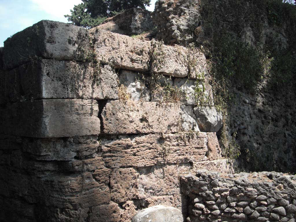 Porta Stabia, Pompeii. May 2011. Detail of south wall on east side. Photo courtesy of Ivo van der Graaff.
According to Van der Graaff-
“The Pompeii Archaeological Research Project: Porta Stabia (PARP:PS), run by the University of Cincinnati, has excavated at the Porta Stabia as part of a wider investigation into the adjacent urban district (see Fig. 1.3).    ………………………
The study campaign revised one important element in the construction sequence of the gate.
A comparison between period photographs dating to the turn of the twentieth century against a detailed drawing from Giuseppe Fiorelli published in 1873 attest that a restoration of the gate occurred somewhere between the 1890’s and the 1920’s (Note 86).
The reconstruction included the addition of at least two courses on both bastions, as well as the placing of the spout carved in the shape of a lion head that workers had found nearby. It had vanished by the time Maiuri began his work in the late 1920’s. As a reminder of the reconstruction, the restored courses are composed of a brown tuff stone to serve as a contrast to the lower courses in yellow travertine.”
See Van der Graaff, I. (2018). The Fortifications of Pompeii and Ancient Italy. Routledge, (p.20)