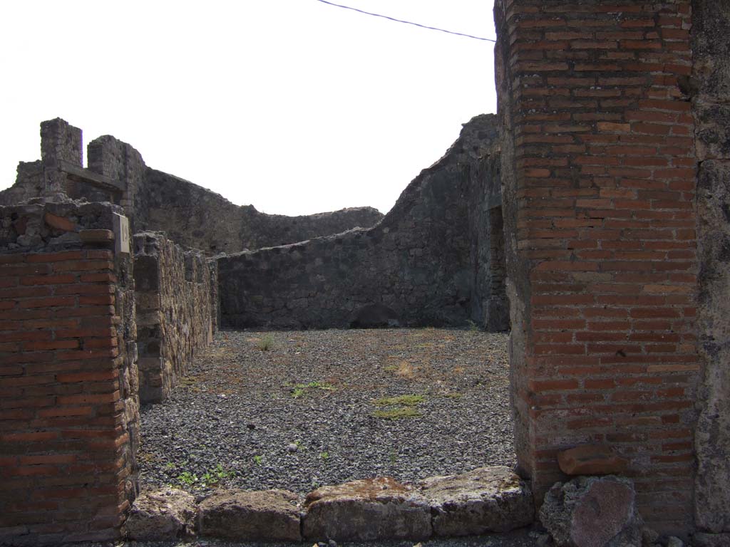 VII.7.19 Pompeii. September 2005. Looking south from entrance directly into atrium.
According to Eschebach, in the middle of the south wall would have been a lararium.
On the left, east side, can be seen doorways to an oecus with stairs to upper floor, and a triclinium fenestratum.
See Eschebach, L., 1993. Gebäudeverzeichnis und Stadtplan der antiken Stadt Pompeji. Köln: Böhlau. (p.302)
According to Boyce –
in the centre of the south wall of the large central room was a rectangular niche (h.0.48, w.0.45, d.0.22, h. above floor 1.65); 
in the west wall, near the floor, was an arched niche (h.0.92, w.0.55, d.0.20, h. above floor 0.55).
The latter was called the lararium by Fiorelli, although the former was more like the usual shrine.
See Boyce G. K., 1937. Corpus of the Lararia of Pompeii. Rome: MAAR 14. (p.68, no.300)