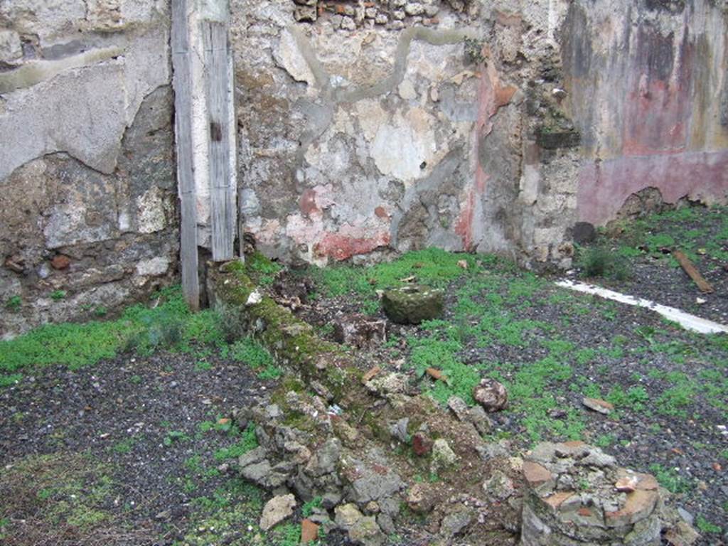 VII.12.26 Pompeii. December 2005. West wall of garden area, north portico and doorway to triclinium.
According to Boyce –
there was a lararium painting (h.2.13, w.2.18), on the west end of the north portico done on a white background.
The Genius stood in the centre, pouring a libation from a patera upon an altar; 
on each side of him is a Lar in variegated tunic and red pallium and holding rhyton and patera. 
Below them, two serpents were approaching an altar.
See Boyce G. K., 1937. Corpus of the Lararia of Pompeii. Rome: MAAR 14. (p.71, No.321).
See Giacobello, F., 2008. Larari Pompeiani: Iconografia e culto dei Lari in ambito domestico. Milano: LED Edizioni, (p.194, no.80)