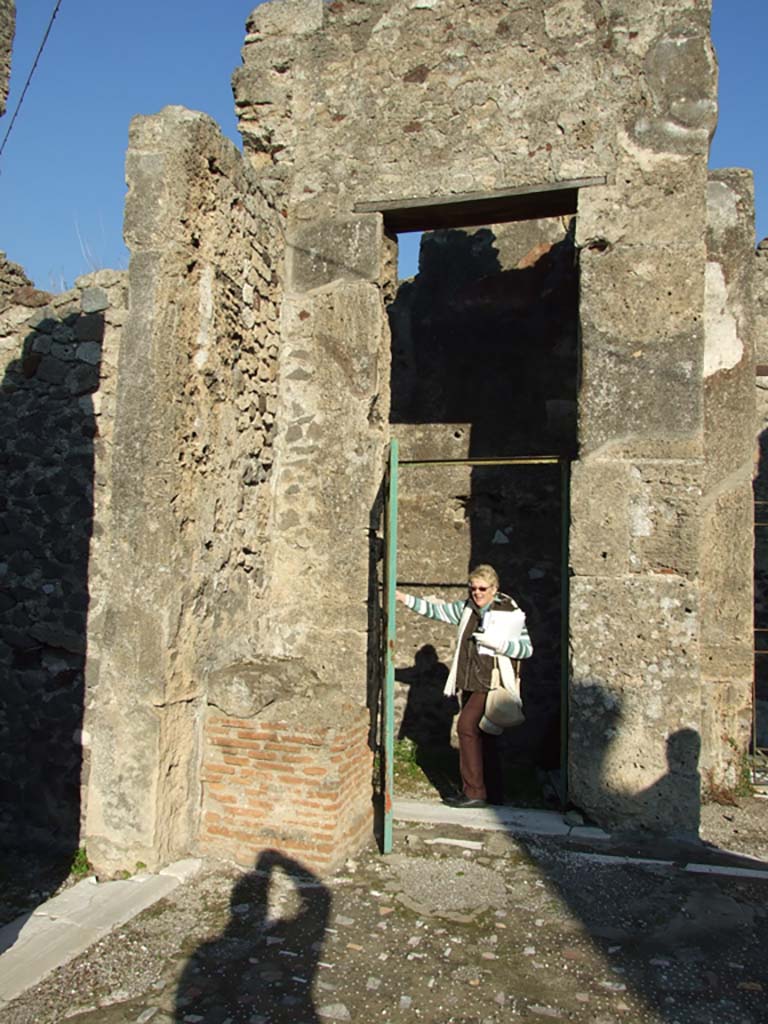 VII.16.13 Pompeii. December 2007. Doorway to room 5, on left, and to room 3, in centre.
Doorway from atrium to rooms 3 and 4 and entrance doorway from VII.16.14.
On the left of the doorway are the remains of the brick base of a shrine to the household gods. 
According to Boyce, in the north-east corner of the atrium stood a ruined brick base.
It was later in date than the stucco on the wall and is described by Fiorelli as “l’altare dei sacrifizi”.
Mau described it as “die Basis der Larenkapelle”.
See Boyce G. K., 1937. Corpus of the Lararia of Pompeii. Rome: MAAR 14.  (p. 73, no. 340).