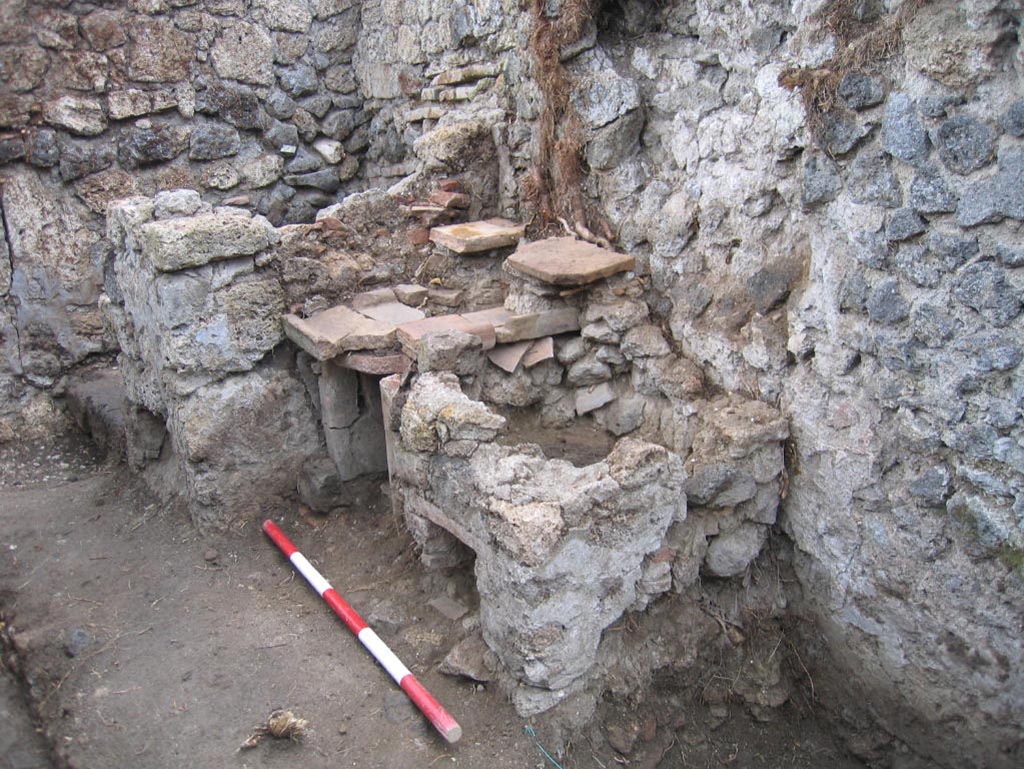 VIII.7.10 Pompeii. August 2005. Looking south-east in kitchen area towards hearth at east end of south wall.
The remains of the lararium niche may be partly visible on the upper right of centre of the photo.
Photo courtesy of Pompeii Archaeological Research Project: Porta Stabia.
According to Mau -
“Next to the hearth there was the usual painting of the Lares, and a niche.”
See Mau in BdI, 1875, (p.167) (p.166-169 - La quarta casa).