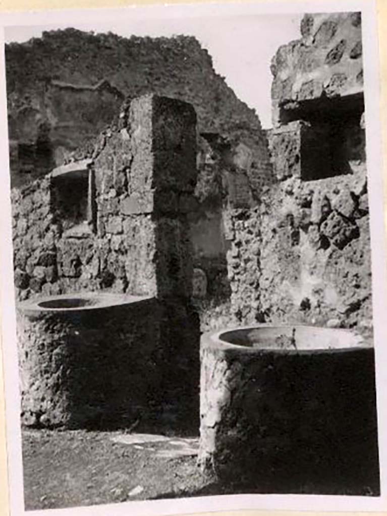 IX.1.3/33 Pompeii. Pre-1943. 
Looking south-west from oven towards two small tubs, above both were niches. Photo by Tatiana Warscher.
See Warscher, T. Codex Topographicus Pompeianus, IX.1. (1943), Swedish Institute, Rome. (no.9), p. 22.
According to Boyce –
“Against the wall facing the oven stand two small masonry basins and in the wall above each is a rectangular niche called by Fiorelli “la nicchia dei Penati”; there remains today no indication of religious purpose.”
See Boyce G. K., 1937. Corpus of the Lararia of Pompeii. Rome: MAAR 14, (379).