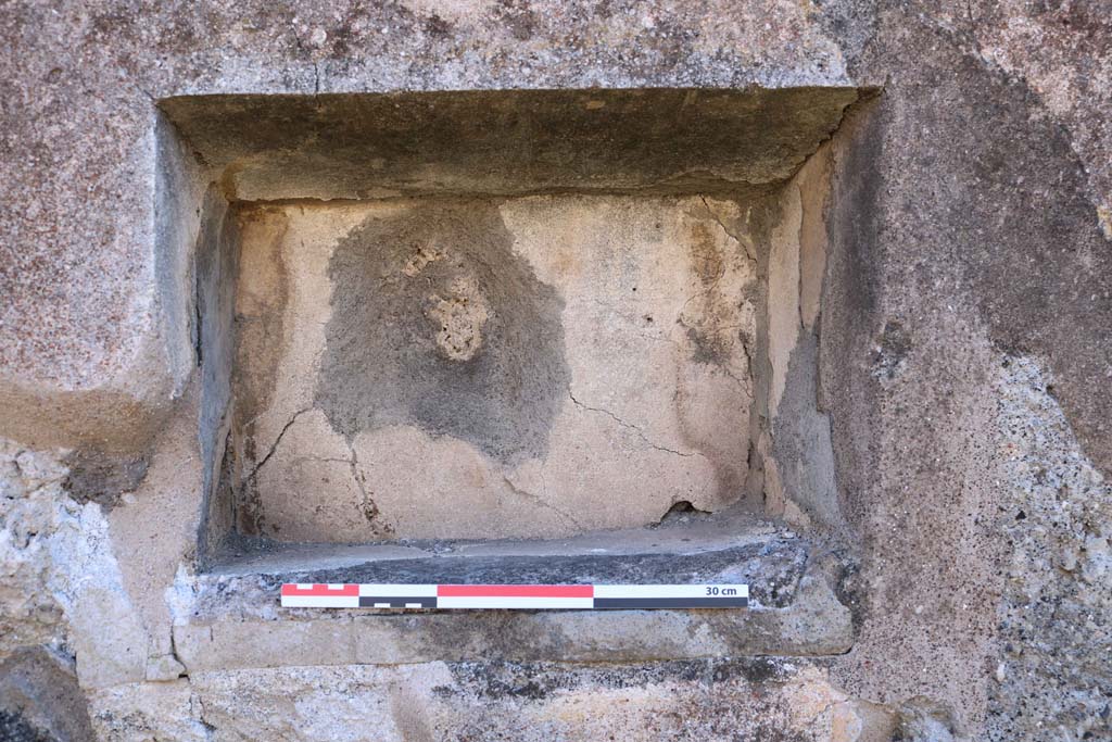 IX.2.7 Pompeii. December 2018.  Detail of niche in south wall of shop room. Photo courtesy of Aude Durand.
According to Boyce –
In the south wall is a rectangular niche (h.0.32, w.0.44, d.0.22, h. above floor 1.45). 
The excavation report stated this was a lararium. He gave the reference Bull. Arch. Nap., N.S.1, 1853, 25.
See Boyce G. K., 1937. Corpus of the Lararia of Pompeii. Rome: MAAR 14. (p. 80, no. 392).