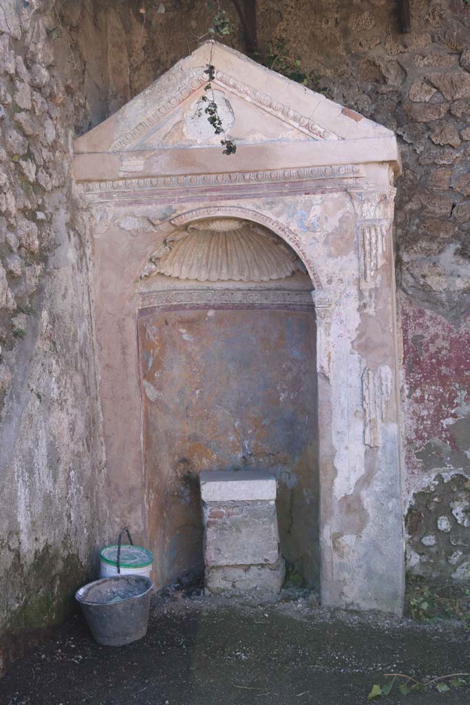 IX.6.8 Pompeii. February 2020. 
Aedicula lararium in garden area 9. Photo courtesy of Aude Durand.
According to Boyce –
In the south-west corner of the garden area stands an aedicula – a rectangular masonry structure (1.36 by 0.67, h.2.65) with gable roof.
The front side is ornamented with an aedicula façade surrounding the opening of an arched, semicircular niche. 
There is no podium, for the niche extends to the floor. ………….
The interior of the niche is coated with yellow stucco, and upon it are painted a leafy tree with birds flying about it, and on each side, Cupids and marine monsters. The vaulted ceiling is ornamented with a stucco shell.
On the floor within the niche, stands a rectangular base, apparently intended to support a statue; it is coated with stucco and upon the front side a mask is painted. …………..
He references – Not. Scavi, 1880, 231; Bull. Inst., 1882, 116. 
See Boyce G. K., 1937. Corpus of the Lararia of Pompeii. Rome: MAAR 14. (p.87, no.432).
See Giacobello, F., 2008. Larari Pompeiani: Iconografia e culto dei Lari in ambito domestico. Milano: LED Edizioni, (p.286 no.V81)