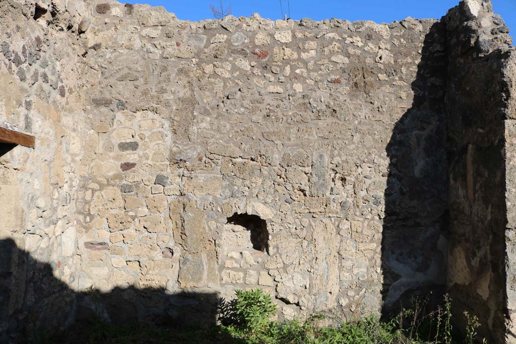 IX.6.e Pompeii. December 2018. East wall with niche. Photo courtesy of Aude Durand.
According to Boyce, in the east wall of the taberna was a rectangular niche (h.0.48, w.0.43, d.0.24, h. above floor 1.10) with peaked ceiling.
Its walls were coated with white stucco outlined in red.
Around it on the wall was a lararium painting, of which only a cornucopia on the left side could be seen when excavated. 
See Boyce G. K., 1937. Corpus of the Lararia of Pompeii. Rome: MAAR 14. (p.87, no.433) 
According to Sogliano, in the shop a sacred picture was found. 
See Notizie degli Scavi di Antichità, 1879, p. 72.
See Sogliano, A., 1879. Le pitture murali campane scoverte negli anni 1867-79. Napoli: (p. 19, no. 71)