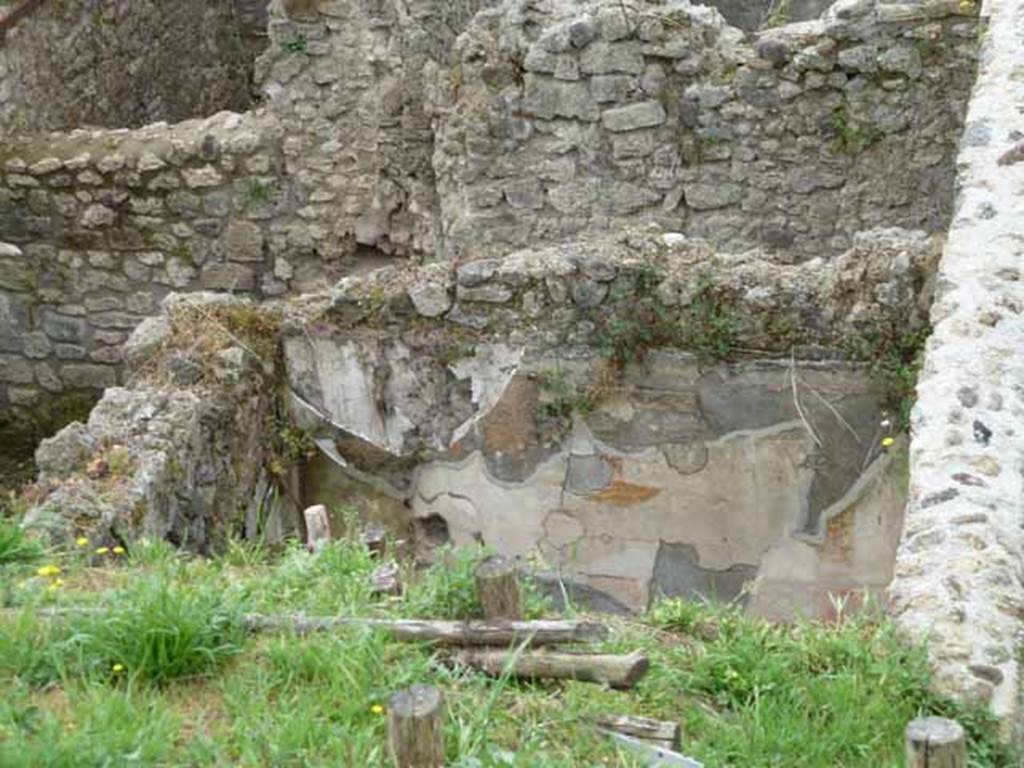 IX.7.16 Pompeii. May 2010. Cubiculum, with kitchen area, at rear, upper left.
According to Boyce, the room behind this wall would have been the kitchen. 
This would have had a lararium painting on the north and west wall (h.1.50, width on north wall 0.60, width on west wall 1.94).
See Boyce G. K., 1937. Corpus of the Lararia of Pompeii. Rome: MAAR 14. (p. 87, no. 436) 
and Boyce gives the reference Bullettino dell’Instituto di Corrispondenza Archeologica (DAIR), 1883, 145. 
See Giacobello, F., 2008. Larari Pompeiani: Iconografia e culto dei Lari in ambito domestico. Milano: LED Edizioni, (p.209, no.105).