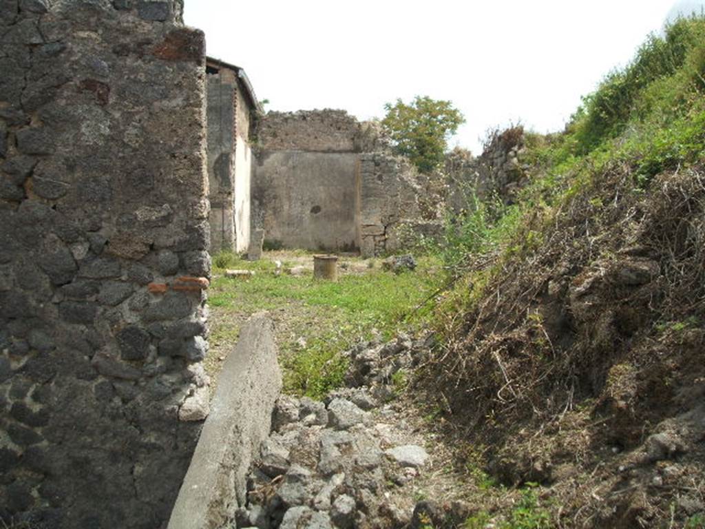 IX.8.c Pompeii. May 2005. Looking east from entrance doorway.
According to Boyce – 
In the west wall of the kitchen, reached from the south side of the peristyle, was a rectangular niche (h.0.44, w.0.65, d.0.26, h. above floor 1.0). On the wall above it was a lararium painting. (See description in Paintings).
See Boyce G. K., 1937. Corpus of the Lararia of Pompeii. Rome: MAAR 14. (p.90, no.452).