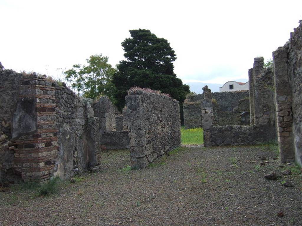 IX.9.4 Pompeii. May 2006. 
Looking south across atrium, with doorway to room ‘g’, triclinium, left of centre, and doorway from room ‘f’, tablinum to garden.
According to Boyce –
In the north wall of the portico which looks out onto the garden from the north side, is a vaulted niche (h.0.40, w.0.40, d.0.12, h. above floor 1.60) – probably the lararium, according to Mau. On the ground before it lies a cube of travertine (0.24) which may have served as altar.
See Boyce G. K., 1937. Corpus of the Lararia of Pompeii. Rome: MAAR 14. (p.91, no.455). 
See Giacobello, F., 2008. Larari Pompeiani: Iconografia e culto dei Lari in ambito domestico. Milano: LED Edizioni, (p.286 no.V82)