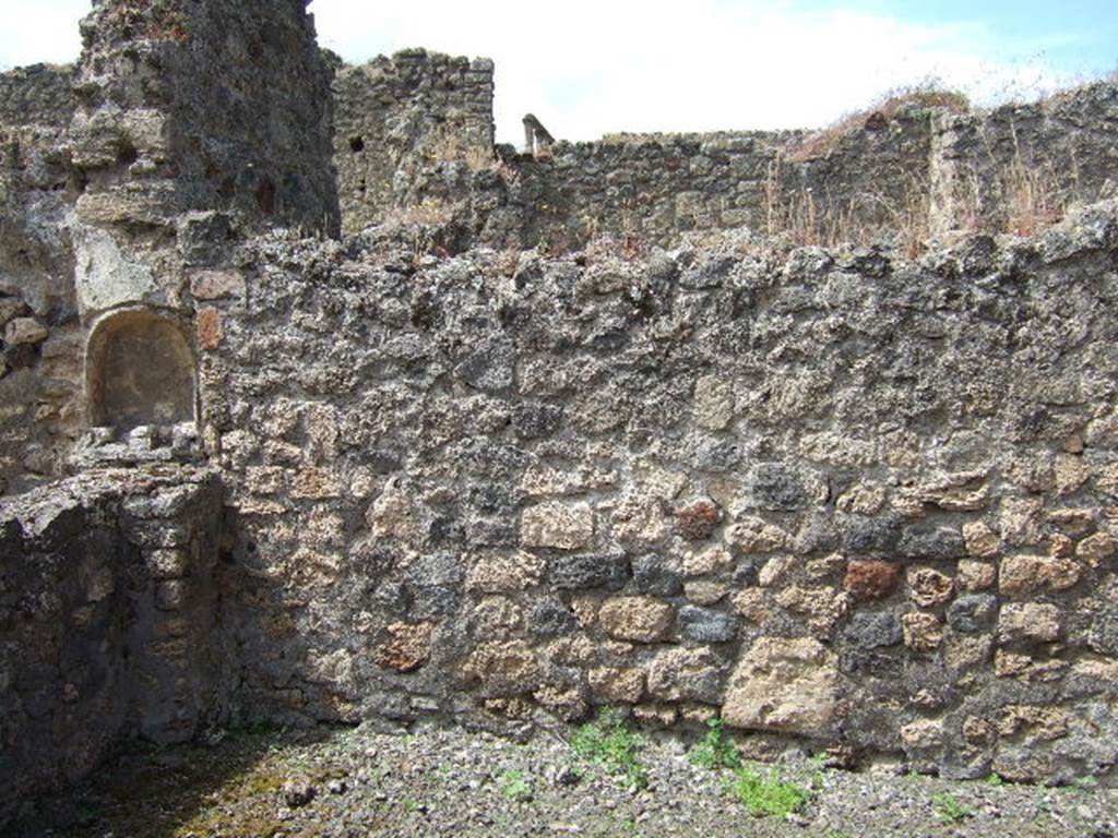 IX.9.6 Pompeii.  May 2006. West wall of wide portico, with lararium niche.
This portico was supported by two pillars, by a masonry arch and a long architrave.
The portico had rustic walls with a high black zoccolo/plinth, which, however, was not continuous: in the west wall, and really in the vertical wall from which the arch originated, a semicircular niche covered in white plaster was hollowed out. Underneath of which, was a matching masonry altar, leaning against the wall and parapet of the inter-columnisation.
See Notizie degli Scavi di Antichità, 1889, p.123.
