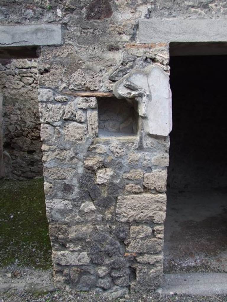 IX.9.c Pompeii. March 2009. North wall of north-west corner of portico.  
According to Boyce –
in the pillar that separates two doorways on the north side of the peristyle was a rectangular niche (h.0.30, w.0.28, d.0.20, h. above floor 1.38).
The niche was adorned with a stucco aedicula façade which consisted of two half-columns supporting a pediment.
In the tympanum was a patera upon a bluish background.
Also according to Boyce, a bronze figure of Hygeia seated upon a throne with her feet upon a footstool, was found in a room to the left of the fauces.
On each side of the throne stood a small tree, around which coiled a serpent.
See Boyce G. K., 1937. Corpus of the Lararia of Pompeii. Rome: MAAR 14. (p. 93, no. 467, and Note 4).
Giacobello described it as a pseudo-aedicula lararium. 
See Giacobello, F., 2008. Larari Pompeiani: Iconografia e culto dei Lari in ambito domestico. Milano: LED Edizioni, (p.287 no.V85)
