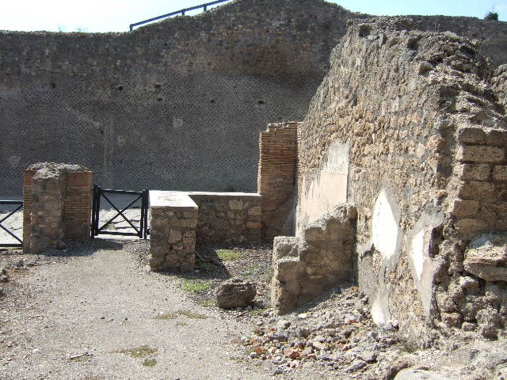 I.2.13 Pompeii. September 2005. Taken from rear. Looking west towards site of ruined small rear room or cupboard, and bar-room onto Via Stabiana and the Little Theatre.  On the left, behind the brick pilaster separating two doorways, would have been the site of the south wall of I.2.13. I.2.14 is visible on the extreme right of the picture.