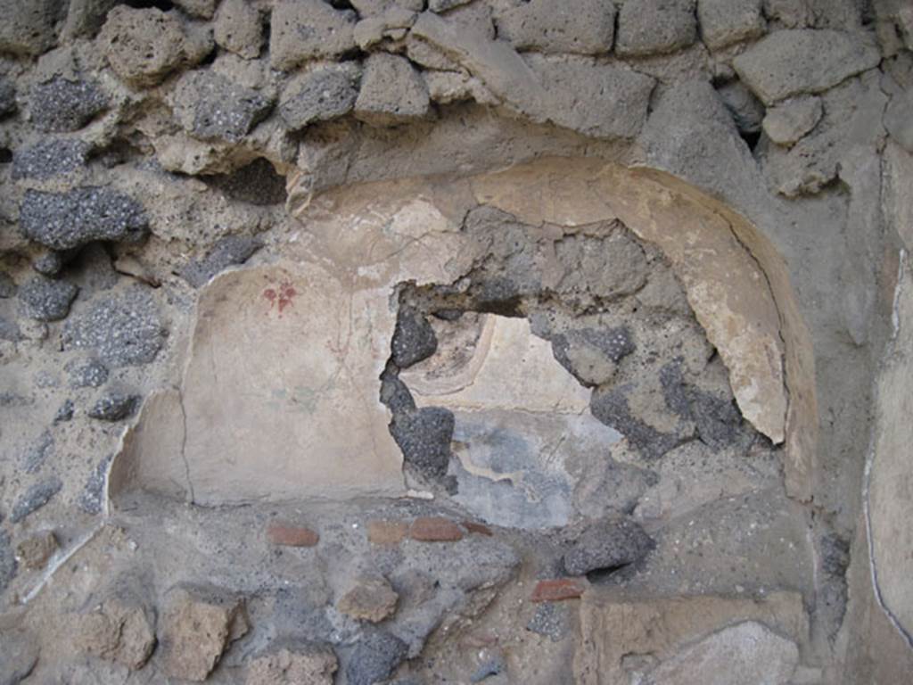 I.3.5 Pompeii. September 2010. Detail of niche in rear east wall on south side. Photo courtesy of Drew Baker.
According to Boyce –
In the rear room behind the entrance at No.5, in the east wall is a broad arched niche (h.0.57, w.1.07, d.0.25, h. above floor 1.25).
Its walls were coated with white stucco and adorned with flowers and plants, painted in red, blue and green.
Eventually, a layer of red stucco was spread over the top, and since peeling off, had revealed the earlier layer underneath.
See Boyce G. K., 1937. Corpus of the Lararia of Pompeii. Rome: MAAR 14. (p.24, no.20).