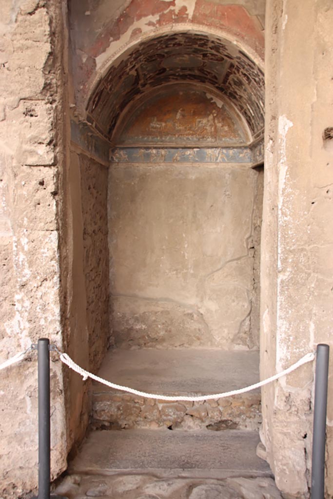I.6.4 Pompeii. October 2022. 
Room 16, looking south into sacellum in south-west corner of atrium. Photo courtesy of Klaus Heese. 
According to Boyce –
On the right of the tablinum is a recess with vaulted ceiling and a figures frieze running around three walls.
This frieze depicts scenes from the Iliad with figures in white stucco relief upon a ground of blue.
It has been suggested, without very good reason, that this room was the lararium.
He quoted Not. Scavi, 1913, 28.
See Boyce G. K., 1937. Corpus of the Lararia of Pompeii. Rome: MAAR 14. (p.25, no.37).