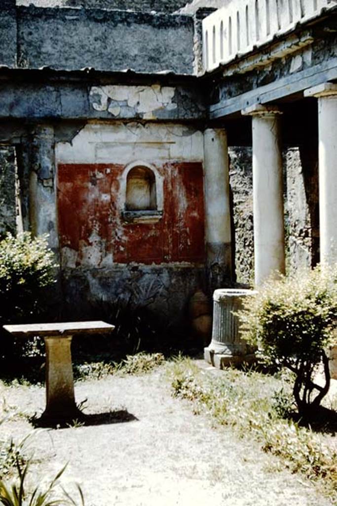 I.7.7 Pompeii. 1961. Lararium niche in west wall in north-west corner.  Photo by Stanley A. Jashemski.
Source: The Wilhelmina and Stanley A. Jashemski archive in the University of Maryland Library, Special Collections (See collection page) and made available under the Creative Commons Attribution-Non Commercial License v.4. See Licence and use details.
J61f0807
According to Boyce, the arched niche was adorned with a stucco aedicula façade and a cornice running around the inside walls. The area of the wall immediately around the niche was painted as part of the decoration, into which the niche was set in a panel. There was no lararium painting and no other indication of religious use. It is called an edicoletta larare in the report and probably was a shrine, as there was no other in the house.
Not. Scavi, 1927, 27.
See Boyce G. K., 1937. Corpus of the Lararia of Pompeii. Rome: MAAR 14. (p.25, no.39)