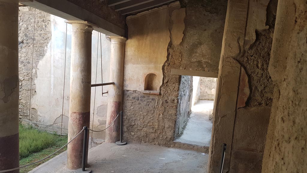 I.7.19 Pompeii. August 2023. 
Looking towards west wall of garden area with niche and doorway to corridor. Photo courtesy of Maribel Velasco.