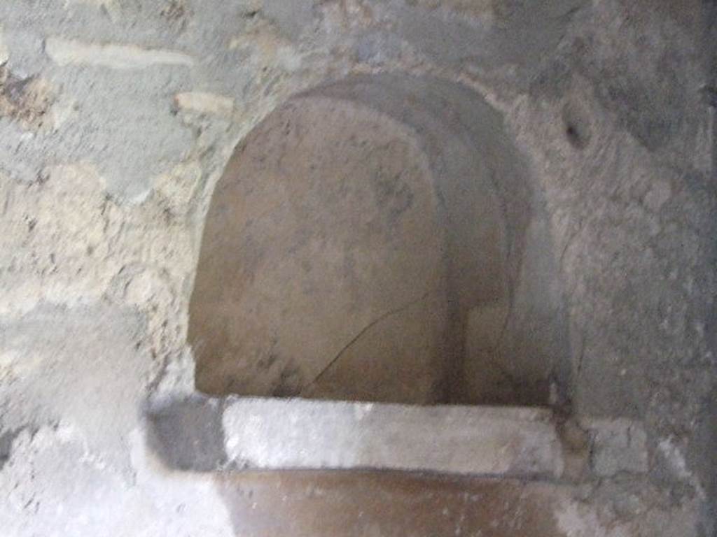 I.11.14 Pompeii. December 2006. Niche in north wall of kitchen. According to Giacobello, this arched niche located near to the bench was covered in white stucco with a protruding brick ledge. See Giacobello, F., 2008. Larari Pompeiani: Iconografia e culto dei Lari in ambito domestico.  Milano: LED Edizioni. (p.151)