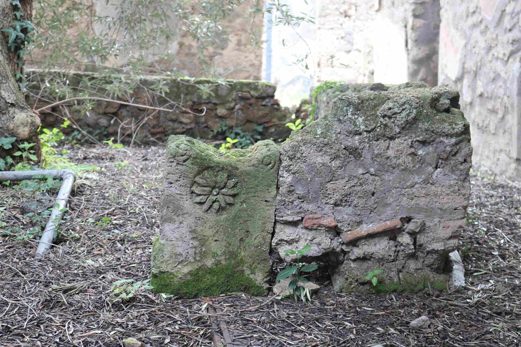 I.12.8 Pompeii. December 2018. 
Room 9, peristyle garden. Low wall in north-west corner with decorative stone, separating portico from peristyle garden. Photo courtesy of Aude Durand.