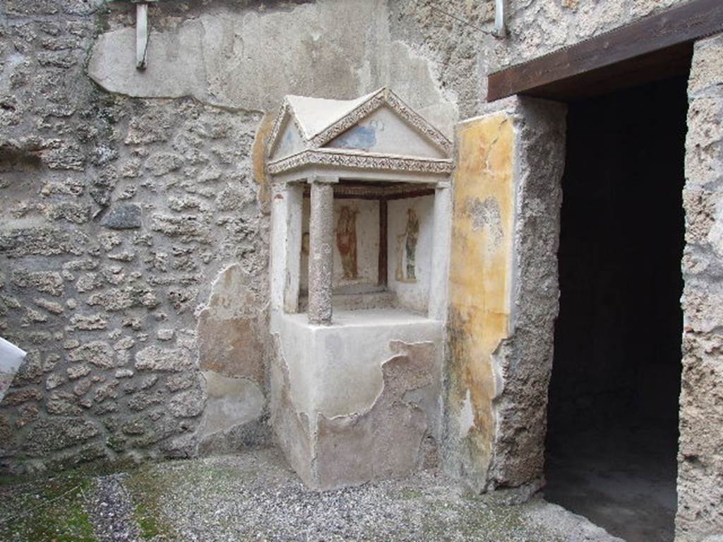 I.16.3 Pompeii. December 2006. Lararium on west side of atrium. 
On the left is a painting of the Genius with cornucopia and an offering plate over a round altar round which a serpent is coils.
On the right is Minerva with shield and lance and an offering plate over a round altar.
See Fröhlich, T., 1991. Lararien und Fassadenbilder in den Vesuvstädten. Mainz: von Zabern. (p.264, L35, taf.5.2-3).
See Giacobello, F., 2008. Larari Pompeiani: Iconografia e culto dei Lari in ambito domestico. Milano: LED Edizioni, (p.234, no.A6)