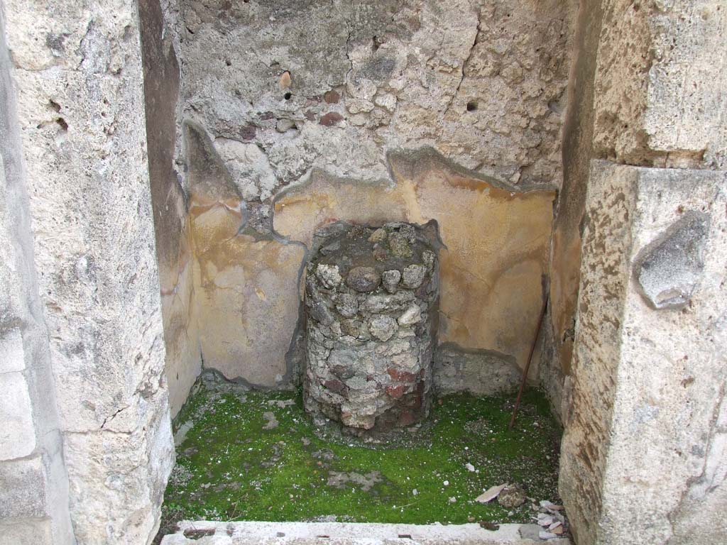 V.1.7 Pompeii. March 2009. Room 5, round altar against south wall in room on east side of entrance corridor.
According to Boyce, this altar is in the form of a half-column, coated with stucco and painted to represent red and yellow variegated marble.
On the yellow background of each side of the altar is painted a serpent coiling among plants.
See Boyce G. K., 1937. Corpus of the Lararia of Pompeii. Rome: MAAR 14. (p. 32, pl.39,4).
According to Giacobello –
“This room was used as a sacrarium (width I.70, depth 0.95) with masonry altar (h.0.90, width 0.40) in the form of a half column, painted in red and yellow in imitation of marble: to the sides of the altar were seen two serpents, no longer conserved.”
See Giacobello, F., 2008. Larari Pompeiani: Iconografia e culto dei Lari in ambito domestico. Milano: LED Edizioni, (p.236, no.A9)