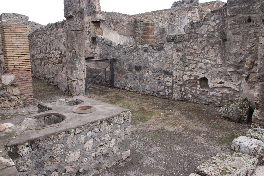 V.1.13 Pompeii. October 2020. Looking towards south side of bar-room, with doorway to rear room, and corridor with arched lararium niche in south wall.
Photo courtesy of Klaus Heese.