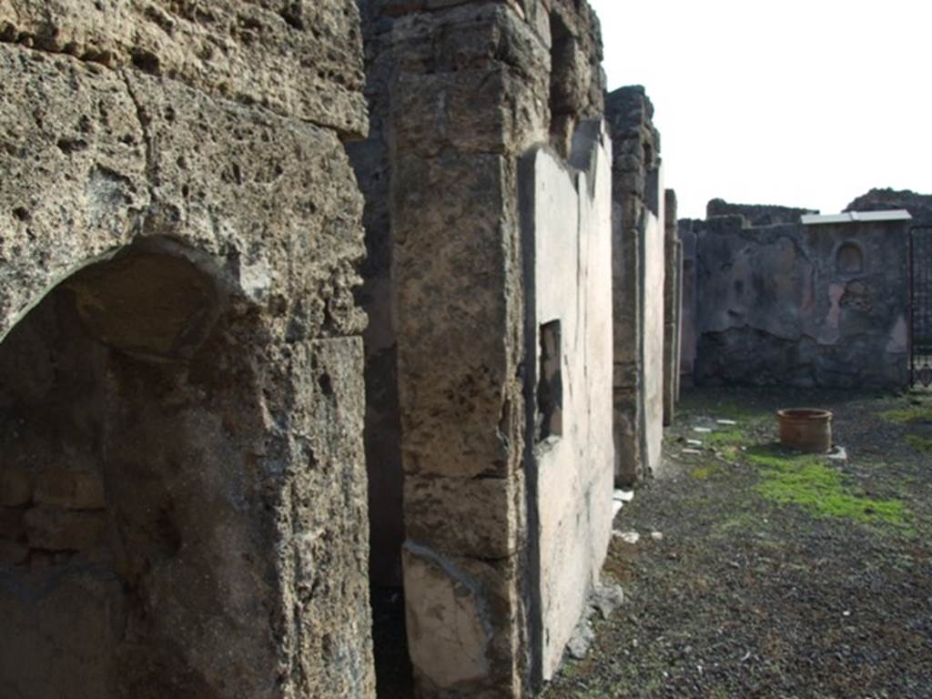 V.2.4 Pompeii. December 2007. Looking south along east wall of atrium across doorways to rooms 7, 8 and 9.
At the far end is the south wall of the atrium with painted niche.
According to Boyce –
“In the south wall of the atrium to the right of the entrance, is an arched niche (h.0.45, 3.0.37, d.0.31, height above the floor 1.68).
The interior is white, outlined with red stripes, and on the back wall is painted the figure of Jupiter (h.0.26).
He is seated upon a throne with a green cushion, is feet upon a footstool; the upper part of his body is nude, the lower part wrapped in a reddish mantle; in his left hand he holds the sceptre, in right the thunderbolt; to the left of his feet stands the eagle which gazes upward at the god.
The vaulted ceiling of the niche, above a band painted in imitation of coloured marble, is decorated with yellow, rose and violet stars upon a white background, and in the centre are painted the bust of Luna with the whip in her hand and, below her, a crescent moon.”
See Boyce G. K., 1937. Corpus of the Lararia of Pompeii. Rome: MAAR 14, (p.34, n. 86, Pl.2,6).
See Giacobello, F., 2008. Larari Pompeiani: Iconografia e culto dei Lari in ambito domestico. Milano: LED Edizioni, (p.237, no.A11)