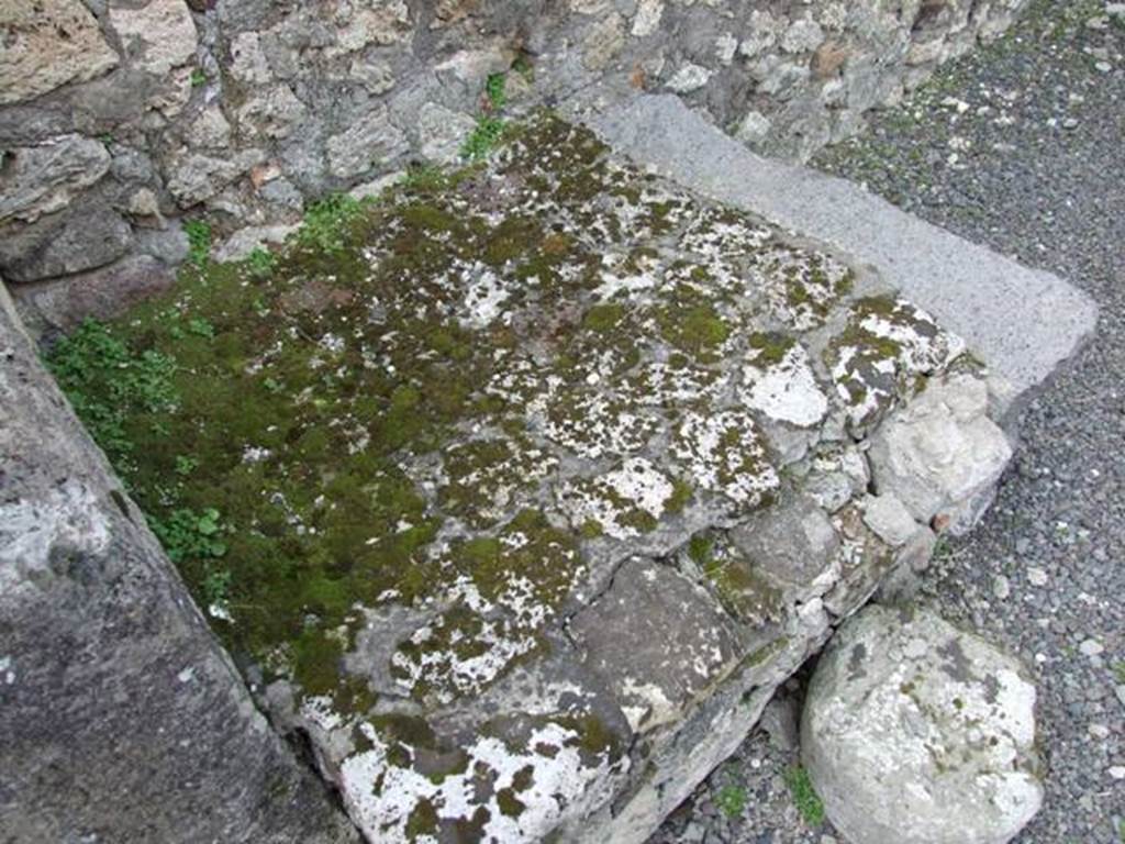 V.2.13 Pompeii. March 2009. South-west corner of thermopolium, and masonry hearth or base. 
According to Boyce, 
“Above the hearth in the south-west corner is a poorly preserved lararium painting: The Genius is represented sacrificing at an altar; on each side originally stood a Lar, only the one on the right being now preserved; further to the right a single serpent approaches an altar.
The above description is taken from Sogliano published in 1879; the descriptions of this house in Rom. Mitt and Not. Scavi, published fifteen and seventeen years later, mention only an altar is visible in a painting, but presumably all refer to the same shrine.”
See Boyce G. K., 1937. Corpus of the Lararia of Pompeii. Rome: MAAR 14, (p.34, no.92).
According to NdS, this thermopolium had a sales counter and a small hearth.
On the west wall Sogliano could see the remains of a painted lararium, with a serpent sliding towards an altar on the left.
At the rear was located the room for the customers, which was bordered by a corridor to the latrine.
See Notizie degli Scavi di Antichità, 1896, (p.438)