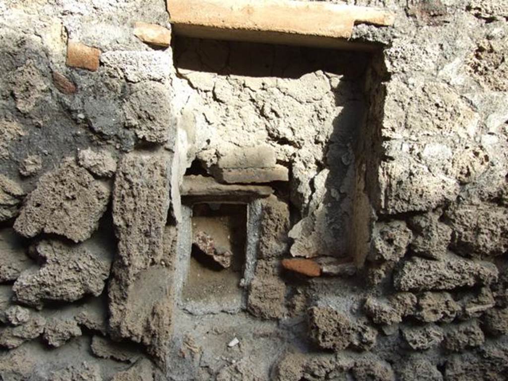 V.2.15 Pompeii. December 2007. Room 11d, rectangular niche. According to Boyce, Mau described this as a lararium.  The walls were coated with white stucco, and in the floor were three holes for the bases of statuettes. The walls around the niche were covered with the same white stucco.  In the wall below, a semicircular receptacle of terracotta was embedded in the floor of an arched niche.  In the bottom of the terracotta was a round hole, as if for drainage, which suggested a connection with the water supply. Today, there is not much remaining.
See Boyce G. K., 1937. Corpus of the Lararia of Pompeii. Rome: MAAR 14.  (no.97 on p. 35)