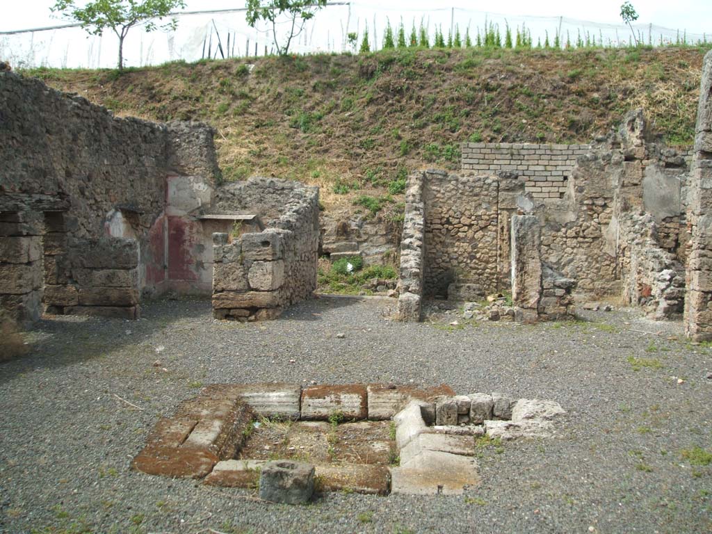 V.2.g Pompeii. May 2005. Looking north across room ‘b’ the atrium, to entrance corridor ‘a’, in centre.
The doorways to room ‘i’, room ‘f’ the kitchen, and room ‘e’ the cubiculum, can be seen on the left of the entrance corridor.
The doorways to room ‘c’ with two entrances separated by a pillar, and room ‘d’ in the north-east corner, can be seen on the right of the entrance corridor.
According to NdS, on the pilaster dividing the fauces (room ‘a’) from the cubiculum on the left of it (room ‘e’), facing south across the atrium, was a lararium niche covered in white plaster.  
On the left side of the lararium was a doorway into a cubiculum, room ‘e’.
See Notizie degli Scavi di Antichità, 1896, (p.419)
According to Boyce, only the pilaster between the fauces and the room to the west had a decorated upper part.
In this pilaster, at a height of I.68m, was a niche for the household gods.
This was coated with white stucco and painted in the Third Style.
See Boyce G. K., 1937. Corpus of the Lararia of Pompeii. Rome: MAAR 14. (p.36, no.104) 
According to CTP, the niche at the south-west terminus of the fauces facing the atrium is now lost. (1982).
See Van der Poel, H. B., 1986. Corpus Topographicum Pompeianum, Part IIIA. Austin: University of Texas. (p.72)