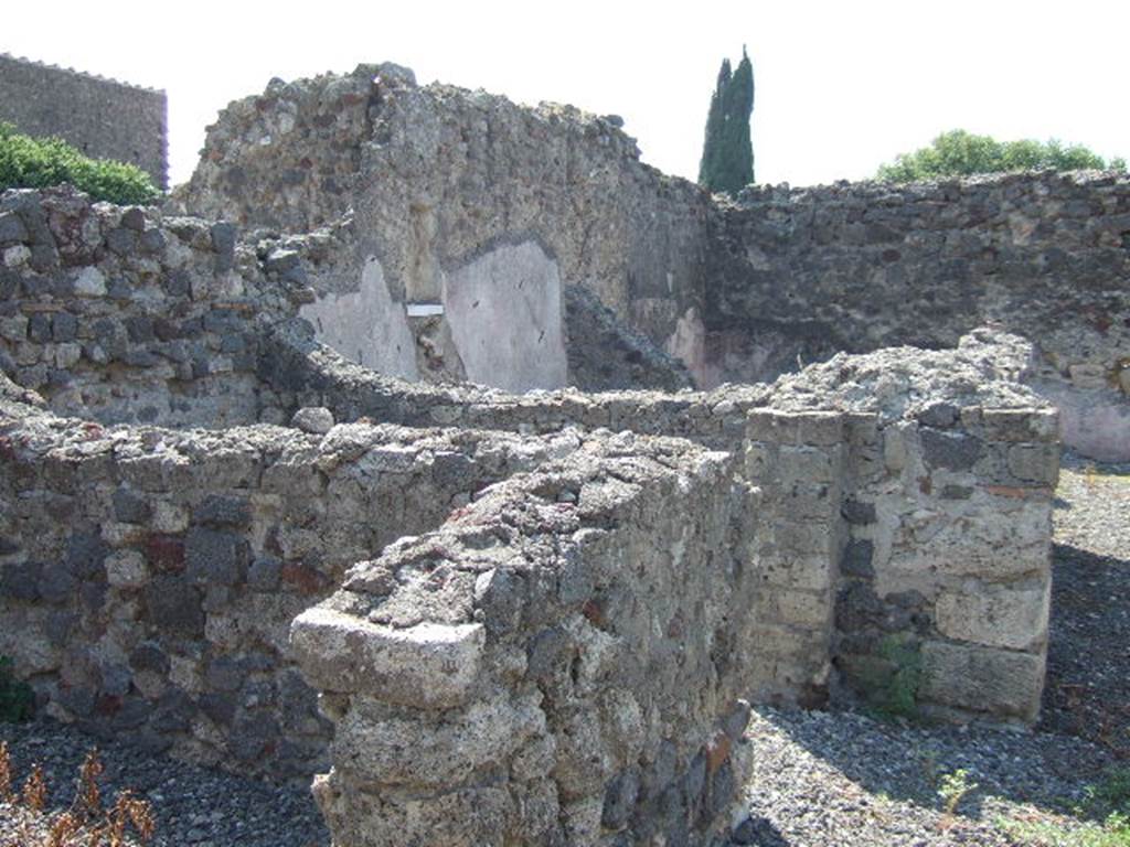 VI.2.28 Pompeii. September 2005. Looking south-west towards rear of house and small garden area. The remains of two cubicula can be seen on the left, and in the upper middle would have been the Oecus.
On the south wall of the oecus, the lararium niche can be made out, above a white shelf. At the rear of the oecus, across the rear of the house, would have been the garden area. According to Giacobello, in the south wall of the Oecus was a square niche with the residue of white plaster and shelf in marble. See Giacobello, F., 2008. Larari Pompeiani: Iconografia e culto dei Lari in ambito domestico.  Milano: LED Edizioni. (p.290)
According to Boyce, in the south wall of the oecus which opens off the garden is a rectangular niche. The walls of the niche are coated with stucco and painted green. The floor of the niche is a thick slab of marble; the reports called it la nicchia per I Penati. See Boyce G. K., 1937. Corpus of the Lararia of Pompeii. Rome: MAAR 14. (p.44, no.143)