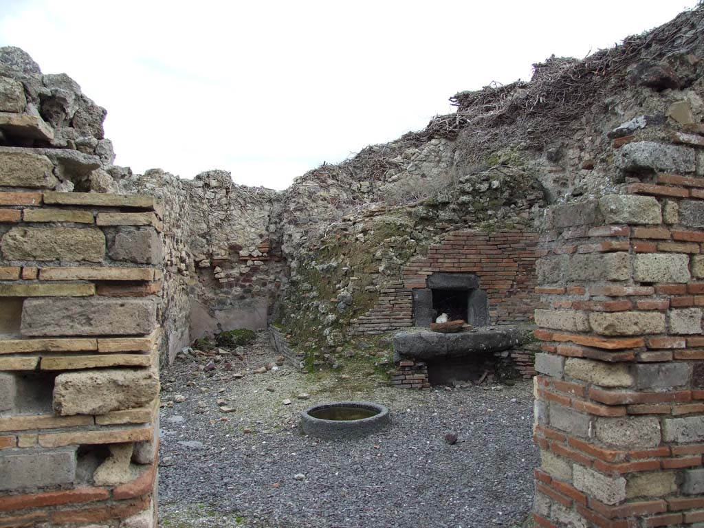 VI.14.34 Pompeii. December 2007. Looking east from atrium towards the oven in the bakery.
At the rear of the wall on the right of this entrance doorway, would be the west wall facing the oven.
According to Boyce, on the west wall facing the oven, above a low table, was a red panel in which two serpents were represented in stucco relief.
One of them is coiled about an altar, the second approaches the same altar from the right; this second serpent is the larger of the two and has crest and beard. Across the top of the panel runs a stucco cornice.
See Notizie degli Scavi di Antichità, 1876, p. 195; Bull. Inst., 1878, 196.
See Boyce G. K., 1937. Corpus of the Lararia of Pompeii. Rome: MAAR 14. (p.53, no.204, with Pl. 28,4).