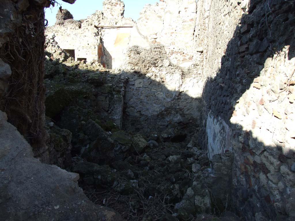 VI.14.39 in foreground, looking north into rear rooms, (“l” (L) and “m”) taken from VI.14.22. December 2007.
These may have originally been underground rooms, the kitchen and wine cellar.
In the background is a room at the east (rear) of the peristyle of VI.14.38.  
According to Boyce, on the east wall of the subterranean kitchen of VI.14.39, was a lararium painting in two zones.
The upper zone contained a sacrificial scene with the Genius on the right of an altar.
On the left was a Camillus, wreathed and wearing a short, girded tunic.
On each side of this group stood a wreathed Lar, carrying rhyton and situla.
In the lower zone, to the right of an altar furnished with an egg, was a red serpent with large crest and beard.
Behind the serpent, at the extreme right of the painting, was a jar.
On the left of the altar some other indistinguishable object, seems to have replaced the second serpent.
Across the top of the upper zone was stretched a garland, and in the background between the figures were painted plants.
See Boyce G. K., 1937. Corpus of the Lararia of Pompeii. Rome: MAAR 14. (p.53, no. 206) 
See Sogliano, A., 1879. Le pitture murali campane scoverte negli anni 1867-79. Napoli: (p. 13, no. 28)
See Giacobello, F., 2008. Larari Pompeiani: Iconografia e culto dei Lari in ambito domestico. Milano: LED Edizioni, (p.179, no.61, for a description of the lararium, no longer conserved in the underground kitchen, due to the house being badly damaged in 1943 bombing).