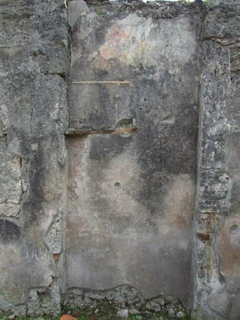 VI.16.27 Pompeii. March 2009. Room B, recess in south wall of atrium.
According to Boyce, the doorway that led from the atrium to the peristyle was walled up, leaving a shallow recess in the south wall.
Within this recess, in the upper left corner, a white panel was marked off by green stripes on both sides. The figure of Jupiter was painted on the panel. He was seated upon a throne, leaning his forehead against his left hand, through the bend of this arm passed a long sceptre.
The lower end of the sceptre rested on the ground., in his right hand he held the thunderbolt. His feet were placed on a footstool and to its left stood an eagle. In the wall below the panel were embedded two broken tiles, one horizontal, the second perpendicular to the first at its west end. The wall space between the painting of Jupiter and the two tiles was decorated with plants painted on a yellow background. The horizontal tile may have served as a shelf for offerings, but the purpose of the two tiles was not clear. Found near the shrine was a terracotta votive altar. Not. Scavi, 1908, 184.  See Boyce G. K., 1937. Corpus of the Lararia of Pompeii. Rome: MAAR 14. (p.59, no.226)