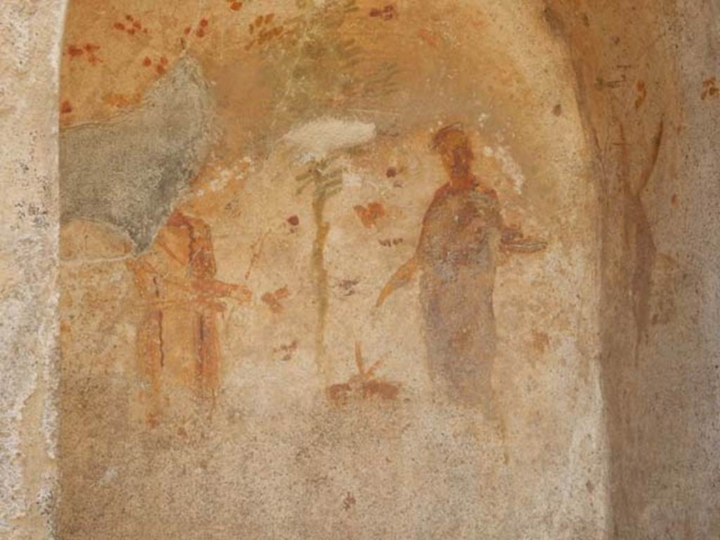 VII.1.46 Pompeii. May 2017. Room 14. Detail of niche lararium.
Photo courtesy of Buzz Ferebee.
According to Fröhlich, there was a painted wall surface with an arched niche on a white ground.
The inside of the niche was moderately to severely faded, especially on the side walls and the bottom of the rear panel.
On the back wall of the niche, on the right, stands Vesta in long purple robe, crowned, sacrificing on a round altar to her right.
On the right side panel a devoted donkey is facing the goddess.
Left of the altar is Vulcan, wearing a yellow robe, his right hand outstretched to the altar holding a pair of tongs and in the left a hammer. 
On his head, the God wore a felt hat. 
A green pine tree behind the altar occupies the centre of the image. 
The background of the rear wall and the side walls and the ceiling is decorated with rough, red and green flowers.
The paintings outside the niche were destroyed.
Outside the niche were once left and right the flanking Lares in green tunics and blue cloaks, with Rhyton with Patera. 
Below the niche was painted a ham, a pig's head and a meat skewer and a snake creeping to the right.
See Fröhlich, T., 1991. Lararien und Fassadenbilder in den Vesuvstädten. Mainz: von Zabern, L79, p. 282 and Taf. 40.2.