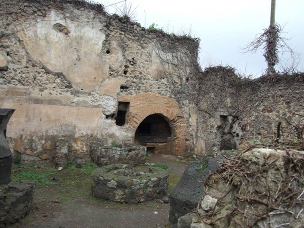 VII.2.3 Pompeii. December 2007. Bakery with mills, basin and oven.
Boyce and Fiorelli state that on one of the walls of the pistrinum was a faded lararium painting. Boyce said that in the centre was an altar and at its side was a seated Vesta, with her right hand she was pouring a libation onto the altar. Behind her shoulder was an ass. On the other side of the altar was the Genius, also pouring a libation onto the altar. 
On each side of this central group was a wreathed Lar, wearing tunic, pallium and high boots, and holding a patera and rhyton. Across the top of the painting was a garland.
See Boyce G. K., 1937. Corpus of the Lararia of Pompeii. Rome: MAAR 14. (p. 61, 247) 
See Pappalardo, U., 2001. La Descrizione di Pompei per Giuseppe Fiorelli (1875). Napoli: Massa Editore. (p. 80)